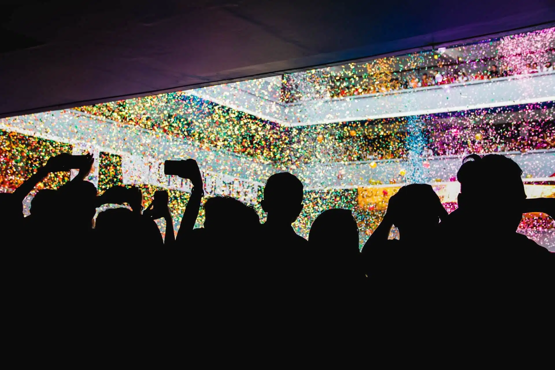 Sagome di persone a un concerto tra luci colorate, tema della FOMO e della paura di perdersi qualcosa